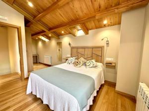 贝加德奥Apartamentos Casa Courego的一间卧室设有一张带木制天花板的大床