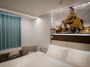 洛迦诺宜必思洛迦诺酒店的酒店客房设有一张床,墙上挂有绘画作品