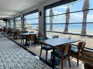 埃尔代克Palmon Hotel的一间带桌椅的餐厅,享有海滩美景