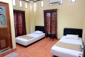 LutanHotel Puri Lembang near Universitas Sulawesi Barat Majene的客房设有两张床、一张桌子和窗帘