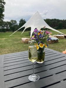 NeerpeltNatuur-like Glamping in Bosland的一杯葡萄酒和一瓶花在桌子上