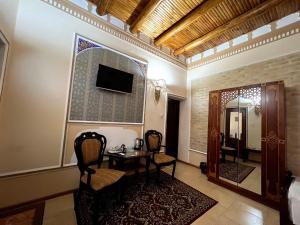 布哈拉Grand Emir Residence的配有桌椅和镜子的客房