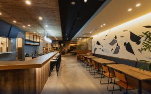 长野Mash Cafe & Bed NAGANO的餐厅内带木桌椅的酒吧