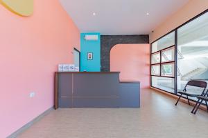 TanjungredepSans Hotel Berau Square的办公室设有粉红色和蓝色的墙壁和书桌