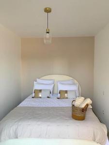 沙泰勒罗Villa chic 3 chambres ,2 SDB的一张带枕头的白色床和一个篮子