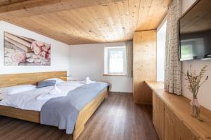 LenzLa Tgoma - Hotel & Restaurant的一间卧室设有一张床和木制天花板