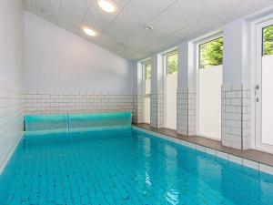 Rygård Strand16 person holiday home in Alling bro的室内游泳池设有蓝色瓷砖地板和窗户。