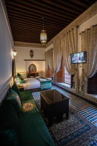 非斯Riad Sidrat Fes的一间卧室配有一张床、一台电视和一张沙发