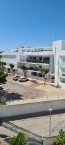 塔维拉Tavira Pimpão - Sea View Flat的一座白色的大建筑,汽车停在停车场