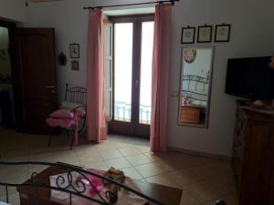 CardileLa Casa Di Lidia的客厅配有粉红色窗帘和电视