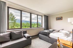 扎科帕内太阳神酒店的一间卧室配有一张床、一张沙发和一个大窗户