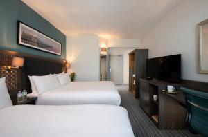 布莱顿霍夫Leonardo Hotel Brighton的酒店客房设有两张床和一台平面电视。