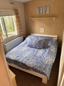 阿丁斯顿4-Bedroom Cosalt Parkhome in Uddingston, Glasgow的一间卧室配有一张带蓝色棉被的床和窗户。