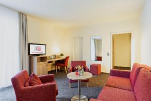 陶努斯山区克龙贝格维多利亚康库德酒店的客厅配有红色椅子和桌子