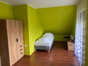 ÖsküAda Vendégház的一间拥有绿色墙壁的卧室和一张位于客房内的床