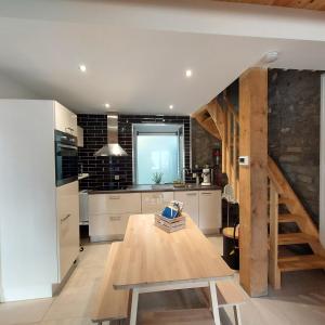 莱斯河畔的汉恩Au Charm'Han的厨房设有木桌和楼梯。