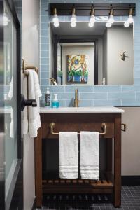 爱荷华The Highlander Hotel的浴室配有盥洗盆、镜子和毛巾