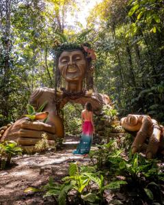 圣拉菲尔ECO HOTEL RIO DE ORO的站在森林中一座巨型雕像前面的女人
