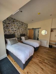 莫珀斯The Star Inn - Harbottle - Near Rothbury - Northumberland的配有2张床的客房,铺有木地板,设有1面墙