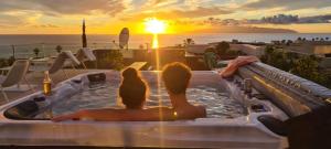 阿德耶Luxury Villa Rebeka - Heated Pool and Jacuzzi的坐在热水浴缸中的一对夫妇,欣赏日落