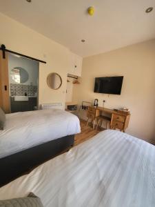 莫珀斯The Star Inn - Harbottle - Near Rothbury - Northumberland的一间卧室配有两张床、一张桌子和一台电视。