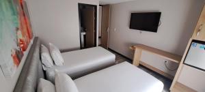 佩雷拉奥拉亚广场酒店的小房间设有两张床和一台平面电视