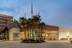 奥兰多Holiday Inn Orlando International Airport, an IHG Hotel的一座楼前有棕榈树的酒店