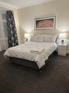 伍德福德格林4 Bed Family Home的一间卧室配有一张大床,设有两个床头柜和两盏灯