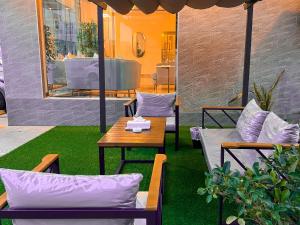 塞拉莱Daar AL Maqam Suites Apartments Salalah的庭院配有桌椅和桌子,并铺有四柱床。