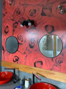 库拉布罗切罗镇Cañas Suites Villa Cura Brochero的浴室的墙上挂有镜子,墙上挂着玫瑰花
