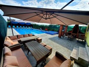 GhioneaAlpha Pool House的一个带桌子和遮阳伞的庭院,毗邻一个游泳池