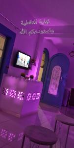 Qarārشاليهات ليله الدرب的一间紫色灯光、桌子和电视的客房