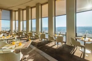 里昂里昂丽笙酒店的餐厅设有桌椅和大窗户。