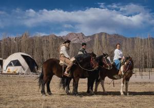 乌斯帕亚塔Cinco Cumbres的三人在带帐篷的田野里骑马