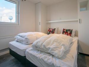 布勒克伦Grote Karekiet 24-22的一间卧室设有两张带白色床单的床和窗户。
