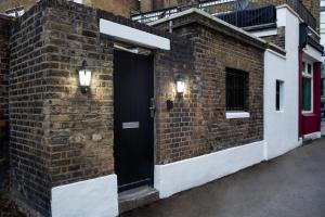 伦敦Eden Grove - Islington - Studio Apartment的砖砌的建筑,上面有黑色的门和灯