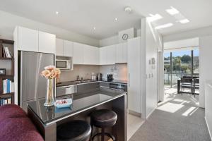 陶波Marina View Apartment - Taupo的厨房配有白色橱柜和紫色沙发
