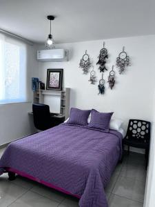 普拉亚斯CasaMuyuyo - Hermosa Casa de Playa a 1h20 de Guayaquil的一间卧室配有一张紫色的床和一把椅子