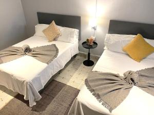 马特瓦拉Hotel El Pedregal的配有2张床的带白色床单和枕头的客房