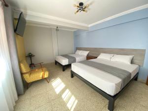 科恰班巴Izza Hotel的一间卧室设有两张床、一台电视和一把椅子