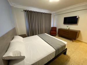 科恰班巴Izza Hotel的一间卧室配有一张床和一台平面电视
