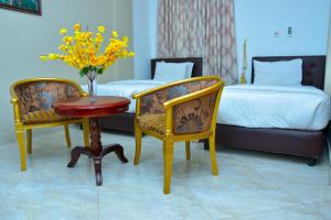 ObuassiMawuli Hotel的酒店客房带两张床和一张桌子以及椅子。
