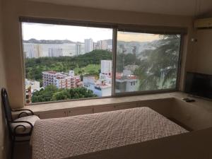 阿卡普尔科Hermosa Villa Puesta al SOL的一间卧室设有一张床和一个大窗户