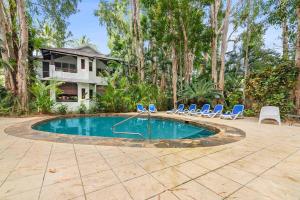 棕榈湾Palm Cove Treetop Spa Retreat的一个带椅子的游泳池以及一座房子