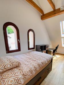 采列Vila Maister的一间卧室配有一张带两个窗户的床和一张书桌