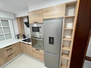 格罗韦Apartamentos Demar Luis Casais的厨房配有不锈钢冰箱和木制橱柜