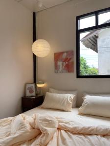 素叻The Ordinary 8的一间卧室配有一张带白色床单的床和一扇窗户。