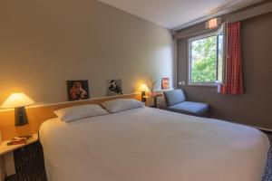 梅里尼亚克ibis Bordeaux Mérignac的卧室配有一张白色大床和一把椅子