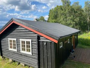 杜姆奥斯Ljoshaugen Camping的黑色的小棚子,有红色的屋顶