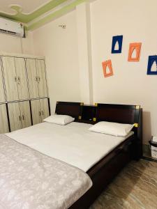 瓦拉纳西Paridhi的一间卧室配有一张铺有白色床单的床,墙上挂着蓝色照片。